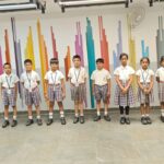 A group of students from Alpine School, a Top CBSE school in Jayanagar, standing in front of a colorful wall in uniform.