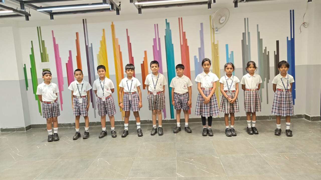 A group of students from Alpine School, a Top CBSE school in Jayanagar, standing in front of a colorful wall in uniform.