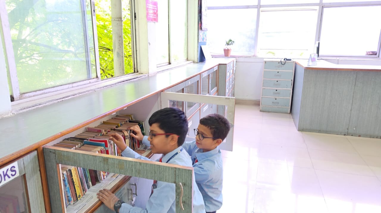 Students selecting books from the library shelves at Alpine School, a top CBSE school in South Bangalore.